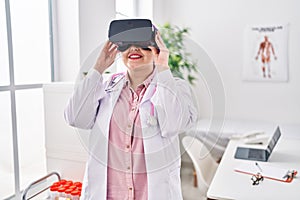 Young beautiful plus size woman doctor using virtual reality glasses at clinic