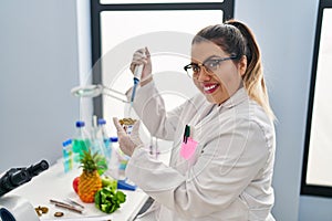 Young beautiful plus size woman scientist pouring liquid on green peas sample at pharmacy