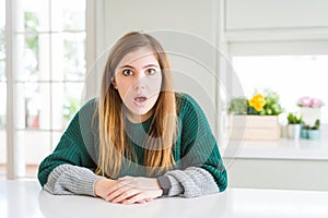 Young beautiful plus size woman wearing casual striped sweater afraid and shocked with surprise and amazed expression, fear and