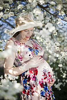 Young beautiful pregnant woman, blooming garden