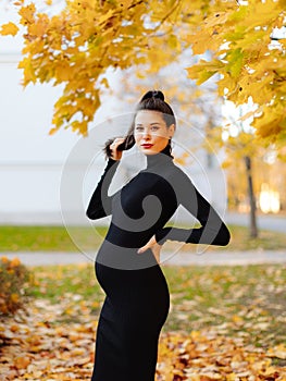 Young beautiful pregnant woman with dark hair in a black tight dress