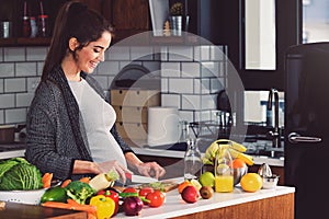 Young beautiful pregnant woman preparing healthy meal with fruites and vegetables