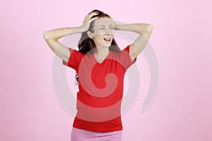 Young and beautiful pregnant woman in red t-shirt using hands holding her head with furious and stress gesture