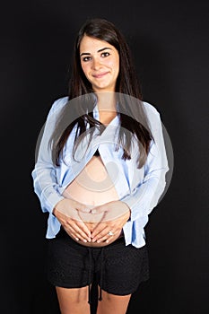 Young beautiful pregnant woman standing on black background
