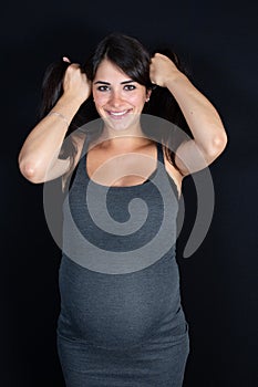 Young beautiful pregnant woman standing hands in hear showers on black background