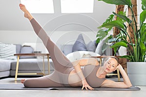 Young beautiful pregnant woman training pilates at home in her living room. Healthy lifestyle and active pregnancy and
