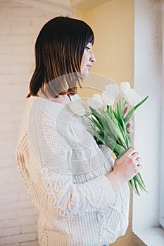 Young beautiful pregnant woman with white tulips