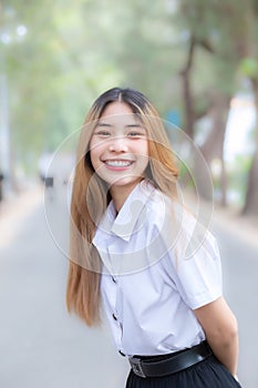 Young beautiful and pretty Asian female college student wearing uniform is standing smiling happily in university campus with