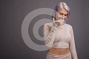 Young beautiful rebel woman with colorful hair against gray back