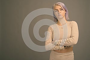 Young beautiful rebel woman with colorful hair against gray background