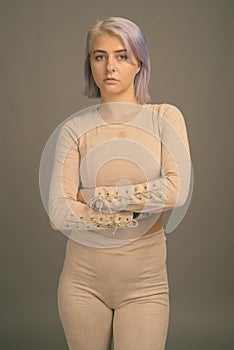 Young beautiful rebel woman with colorful hair against gray background