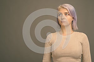 Young beautiful rebel woman with colorful hair against gray background