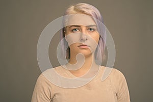 Young beautiful rebel woman with colorful hair against gray background