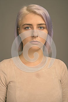 Young beautiful rebel woman with colorful hair against gray background