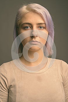 Young beautiful rebel woman with colorful hair against gray background