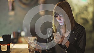 Young beautiful red-haired woman sitting in cafe or bar and using a smartphone