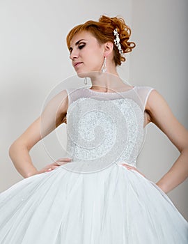 Young and beautiful redhead bride dressed wedding dress posing in studio