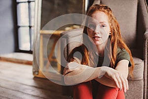 Young beautiful redhead hipster woman with no make up relaxing at home