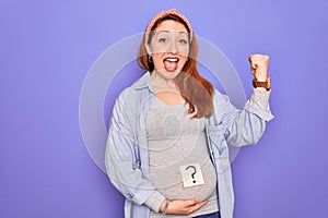 Young beautiful redhead pregnant woman expecting baby with question mark on stomach screaming proud and celebrating victory and