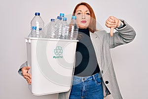 Young beautiful redhead woman recycling holding trash can with plastic bottles to recycle with angry face, negative sign showing