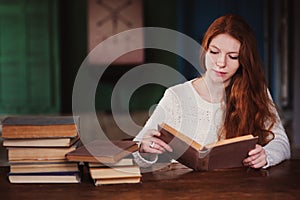 Young beautiful redhead woman relaxing at home in the autumn cozy evening and reading book