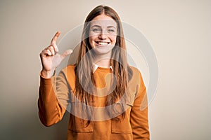 Young beautiful redhead woman wearing casual sweater over isolated white background smiling and confident gesturing with hand