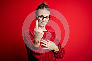 Young beautiful redhead woman wearing casual sweater over  red background Beckoning come here gesture with hand inviting