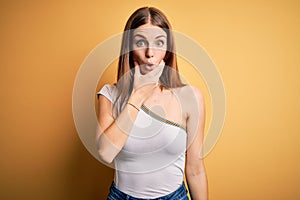 Young beautiful redhead woman wearing casual t-shirt over isolated yellow background Looking fascinated with disbelief, surprise