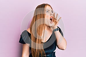 Young beautiful redhead woman wearing elegant and sexy look shouting and screaming loud to side with hand on mouth