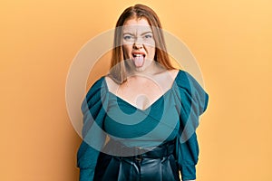 Young beautiful redhead woman wearing elegant and sexy look sticking tongue out happy with funny expression