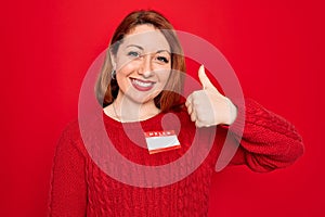 Young beautiful redhead woman wearing sticker presentation with hello my name message doing happy thumbs up gesture with hand