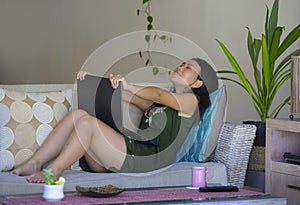 Young beautiful and relaxed Asian Chinese woman on her 20s or 30s sitting happy at living room home sofa couch working or using co