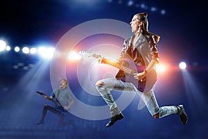 Young and beautiful rock girl playing the electric guitar