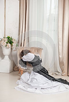 Young beautiful sad crying woman in rococo style medieval dress sitting on the floor