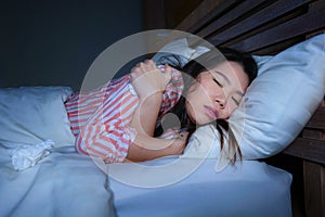 Young beautiful sad and depressed Asian Chinese woman trembling in bed suffering cold and flu at night feeling unwell at nigh in