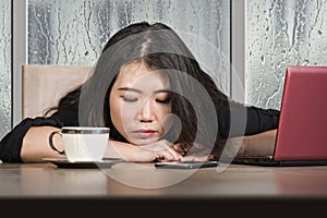 Young beautiful sad and depressed Asian Japanese businesswoman working exhausted and frustrated at office computer desk with rain