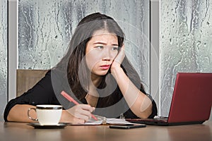 Young beautiful sad and depressed Asian Korean businesswoman working exhausted and frustrated at office computer desk with rain on