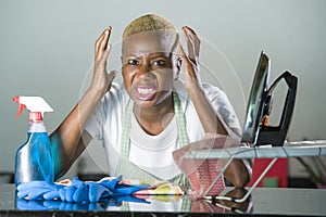 Young beautiful sad and desperate black afro American woman feeling stressed working frustrated at home kitchen with domestic labo