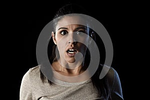 Young beautiful scared Spanish woman in shock and surprise face expression isolated on black