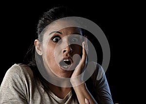 Young beautiful scared Spanish woman in shock and surprise face expression isolated on black