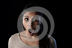 Young beautiful scared Spanish woman in shock and surprise face expression isolated on black