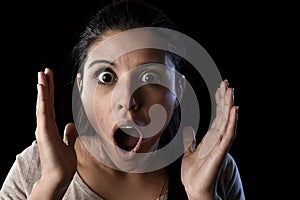 Young beautiful scared Spanish woman in shock and surprise face expression isolated on black