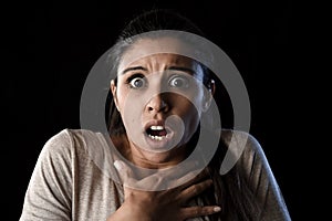 Young beautiful scared Spanish woman in shock and surprise face expression isolated on black