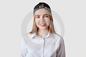 Young beautiful schoolgirl posing in white blouse. Eighteen years old teenage girl looking at camera over bright studio background