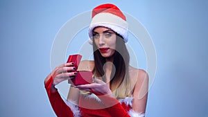 Young beautiful sensual Santa girl dressed sexy red dress and cute Santa hat opens a small red gift box