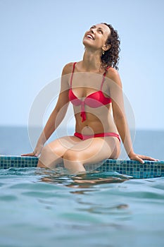 Young beautiful sexual woman sitting on ledge pool