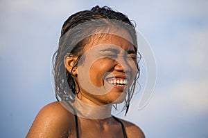 Young beautiful and sexy Asian girl in bikini with wet hair enjoying holidays at tropical beach posing cool laughing happy at the