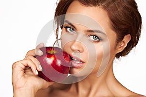 Young beautiful girl with dark curly hair, bare shoulders and neck, holding big red apple to enjoy the taste and are dieting,