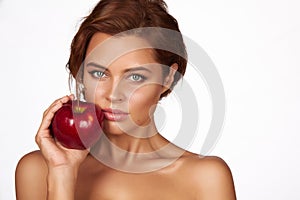 Young beautiful girl with dark curly hair, bare shoulders and neck, holding big red apple to enjoy the taste and are dieting,