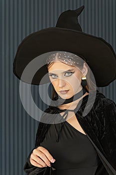 Young beautiful sexy woman wearing a black witch hat. Girl with beautiful makeup and a seductive look. Halloween Outfit